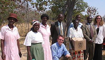 Susanne (far right) and PERSON (kneeling in center) are pictured here delivering books to a Zimbabwean school. The women in pink are the preschool teachers whose training and salaries House Of Stone had funded the three years prior to the visit.