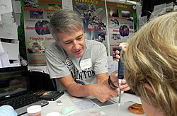 Kyes helping a festival attendee practice pipetting.