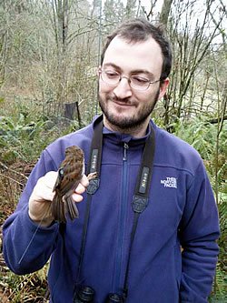 Photo of Caglar Akcay holding a tagged bird