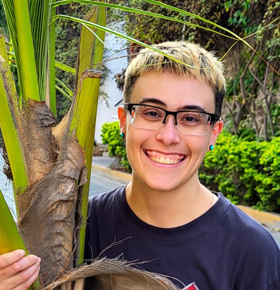 Z Ferguson holding a palm tree trunk