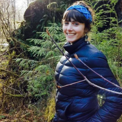  María (Luján) Bazzano walking in a forest looking back and smiling at the camera