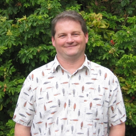 photo of Rich outside smiling in a white print shirt