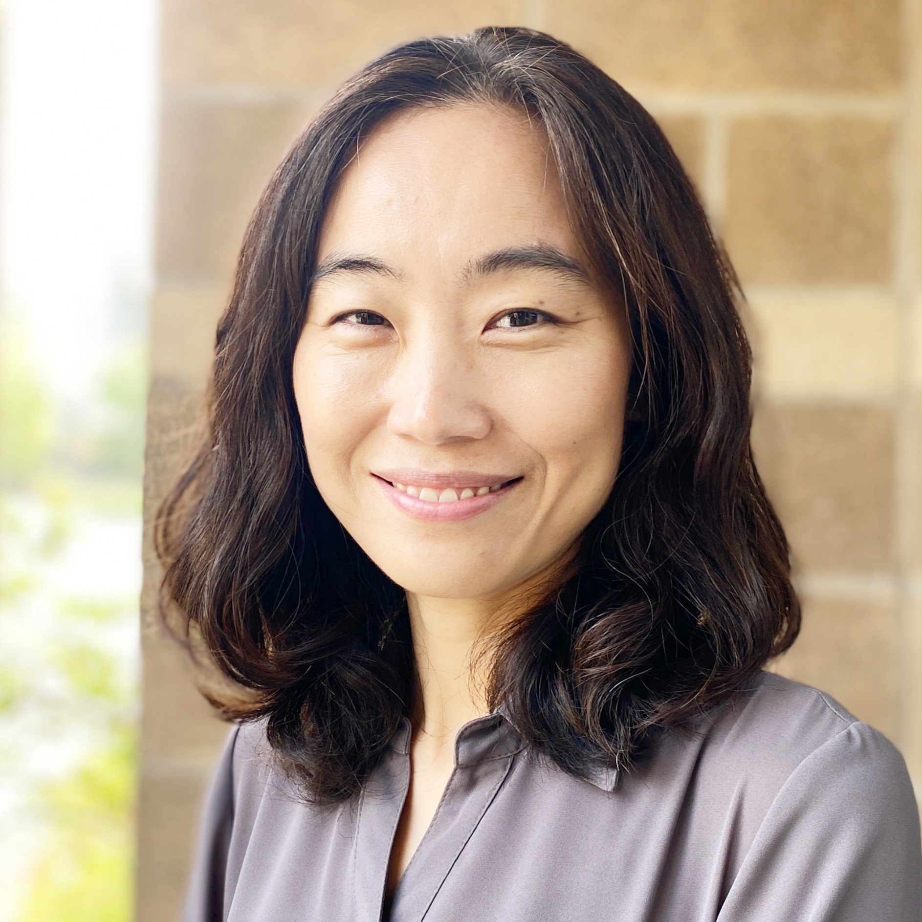 photo of Eun Joo wearing a gray blouse against a brick backdrop